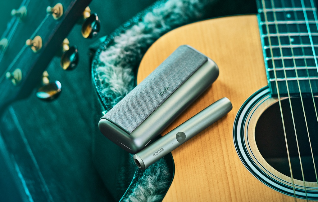 An IQOS ILUMA PRIME device on a guitar.